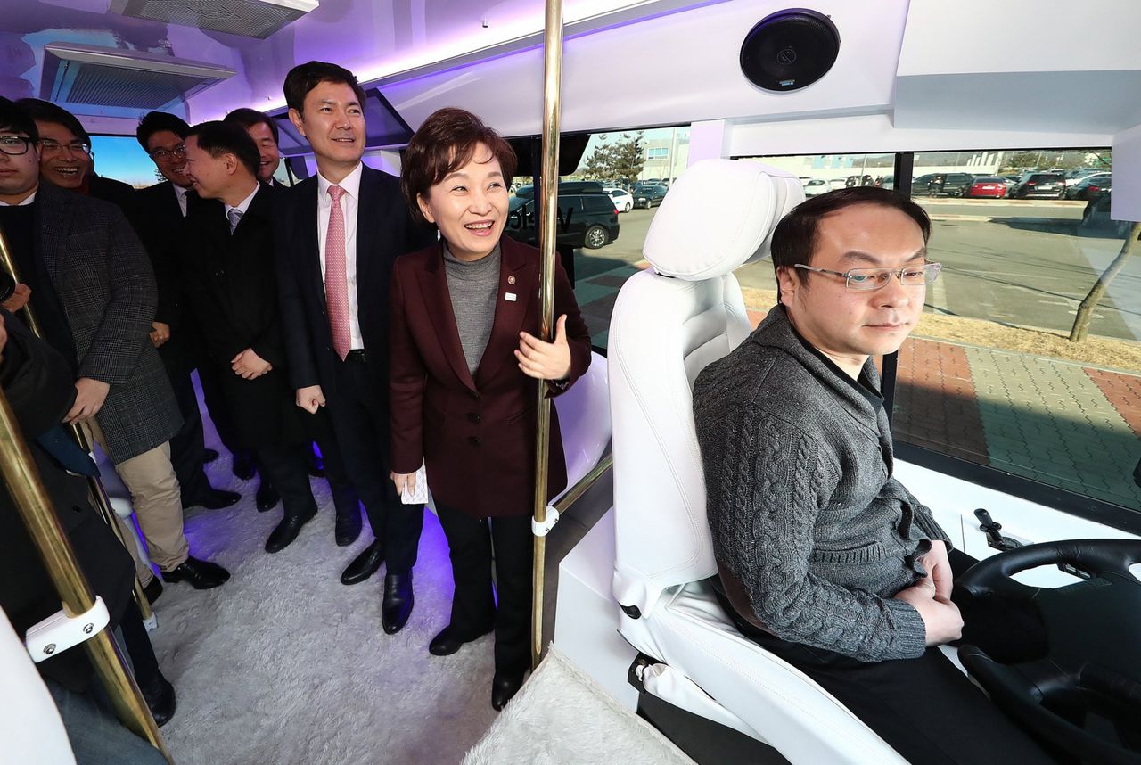 De Zuid-Koreaanse minster van Transport Kim Hyun-mi (tweede van rechts) rijdt mee in een zelfrijdende bus, die gebruik maakt van het 5G-netwerk.