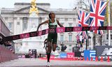 Atlete Sifan Hassan komt als eerste over de finish in Londen, met op de achtergrond Buckingham Palace.