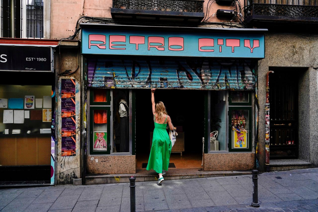 Een vrouw opent haar winkel in het commerciële district in Madrid. Het tweede kwartaal van dit jaar mochten de winkels weer open en dat heeft de consumptie weer aangejaagd.