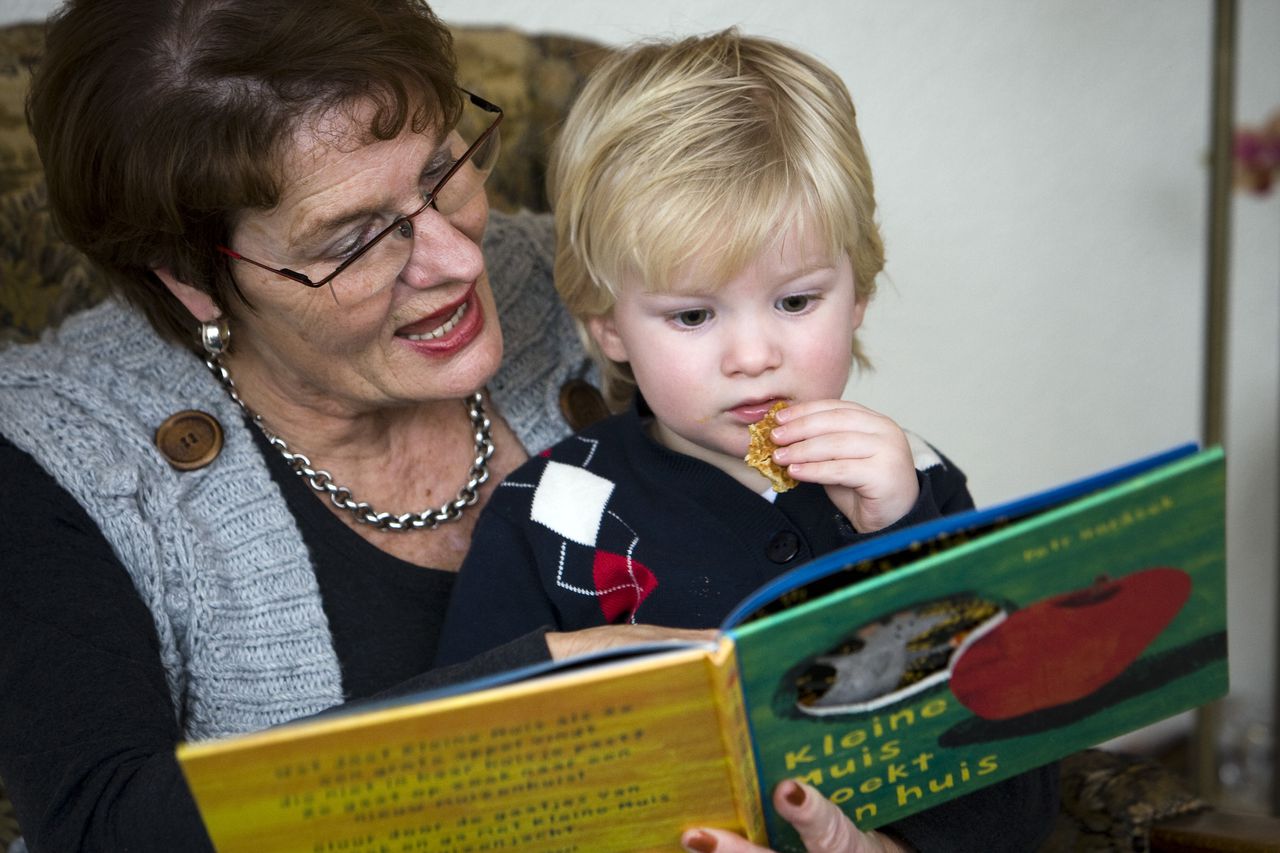 Een oma leest voor aan haar kleinzoon.