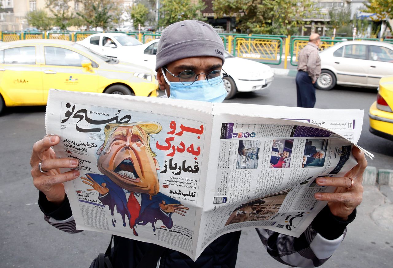 Een man in Teheran leest drie dagen na de Amerikaanse verkiezingen de krant Sobhe Nou met een cartoon van Trump en de tekst 'Loop naar de hel, gokker’.