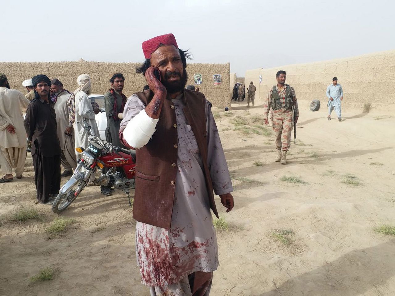 Een man onder het bloed, loopt bellend weg na de zelfmoordaanslag vrijdag op de verkiezingsbijeenkomst van een seculiere partij in Baluchistan. Er vielen zeker 128 doden. Foto Stringer/EPA