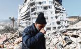 Een man loopt tussen de door de aardbeving ingestorte gebouwen van Gaziantep.