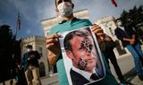 Een jonge man in Istanbul houdt op 25 oktober een foto van de Franse president omhoog met een schoenafdruk in zijn gezicht. 