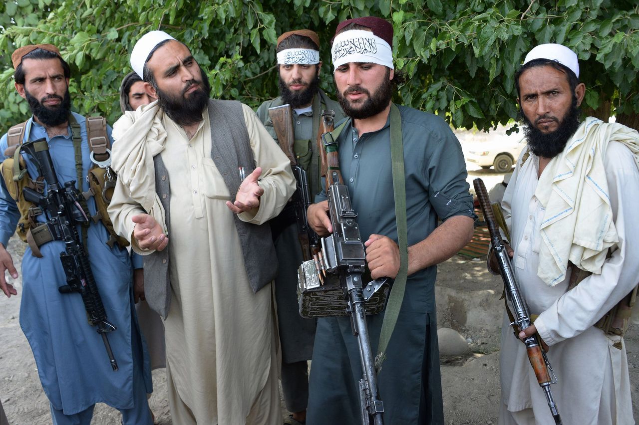 Talibaanstrijders met een bewoner in een buitenwijk van Jalalabad om het staakt-het-vuren te vieren, afgelopen zondag.