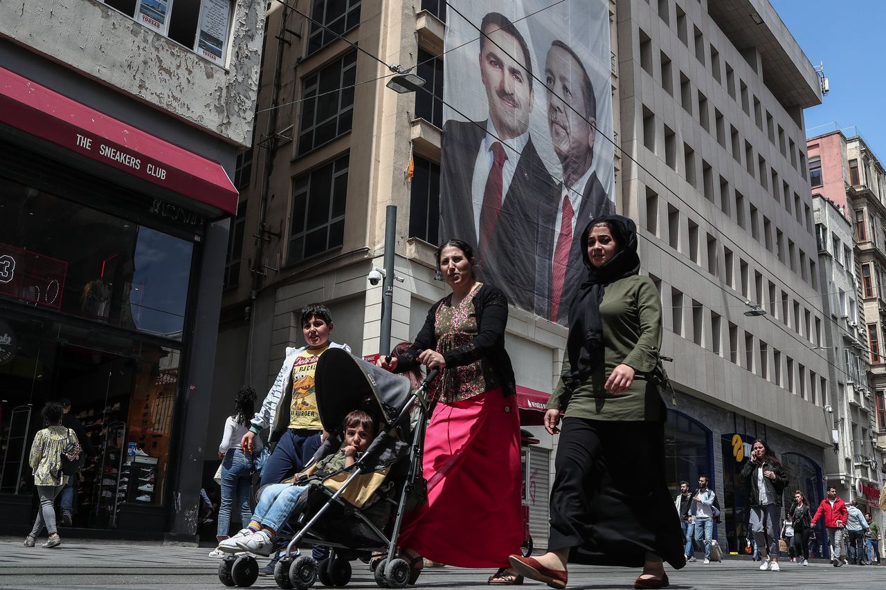 Publiek in Istanbul loopt langs een grote banner waarop de Turkse president Erdogan staat afgebeeld.