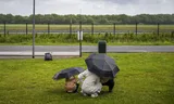 Een gezin schuilt voor de regen voor het aanmeldcentrum van het COA in Ter Apel.