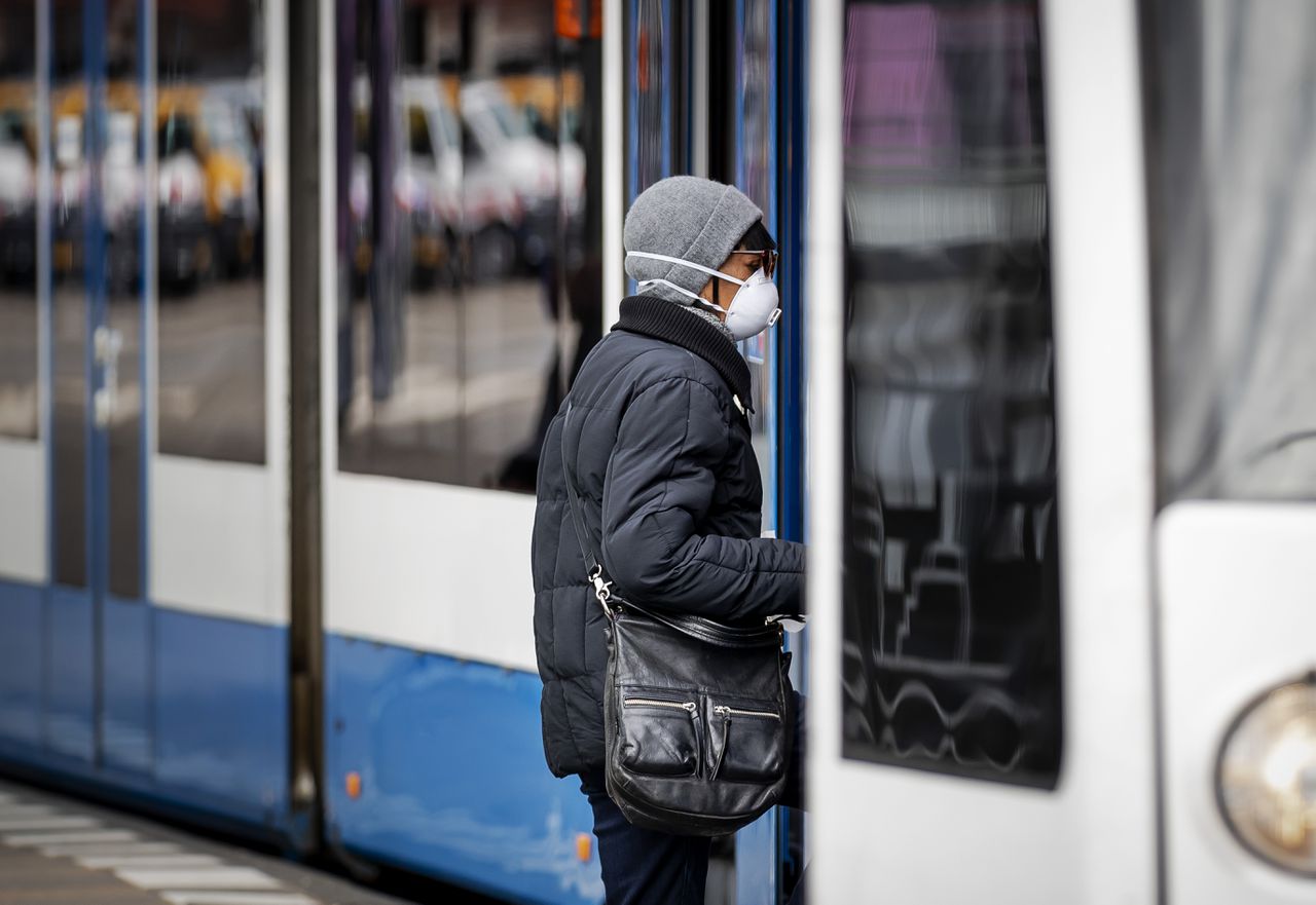 Een passagier met een mondkapje stapt in de tram op het Centraal Station in Amsterdam.