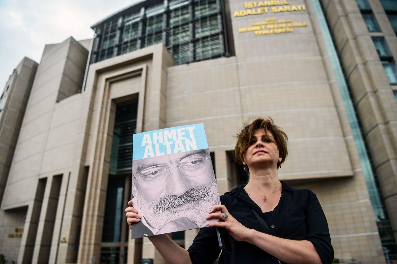 Een journalist poseert met een foto van Ahmet Altan op 19 juni 2017 voor een gerechtsgebouw in Istanbul.