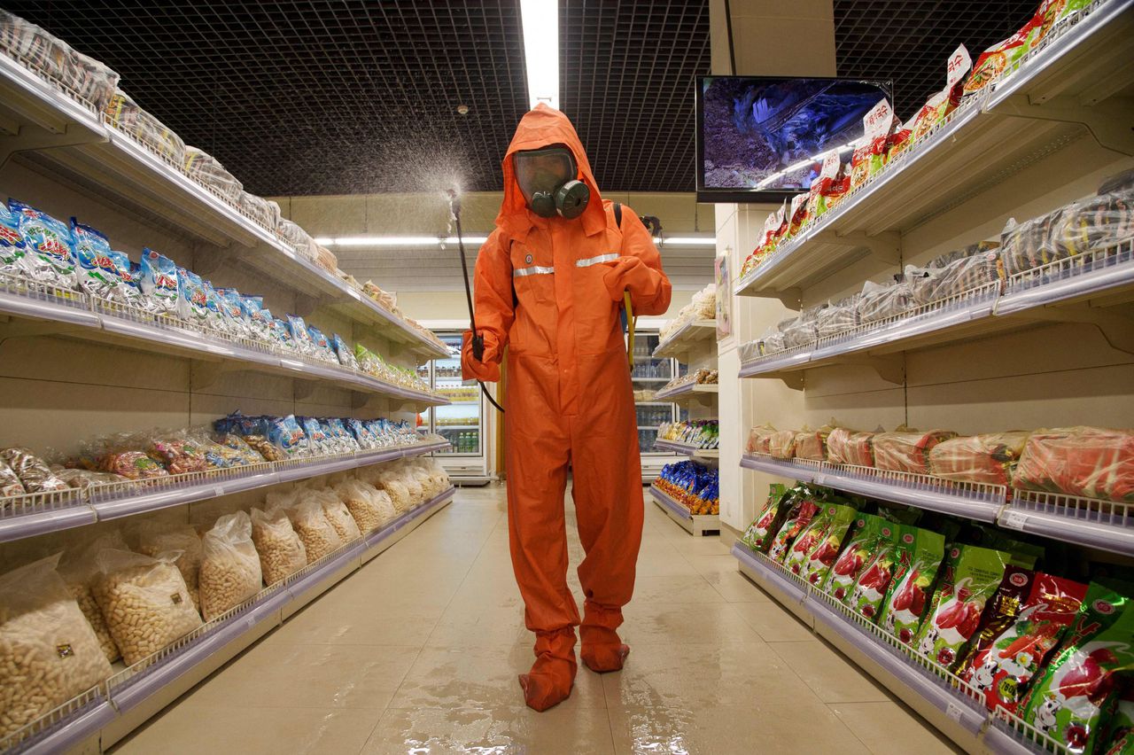 Een gezondheidsmedewerker ontsmet een winkelpad in een supermarkt in Pyongyang.