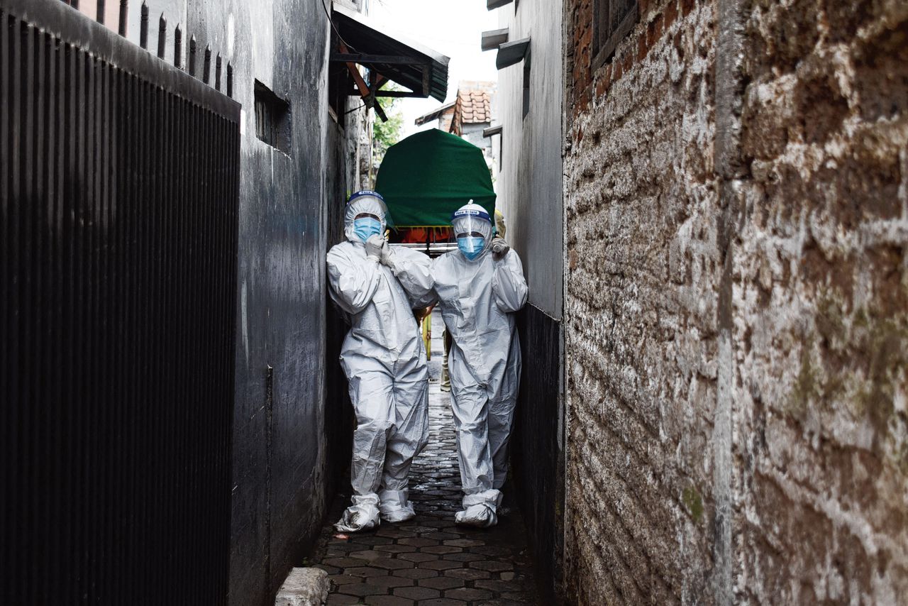 Medisch personeel draagt het lichaam van een man die thuis is gestorven aan Covid-19, in Bandung, Indonesië. In het land is nog maar 5 procent van de volwassenen volledig gevaccineerd.