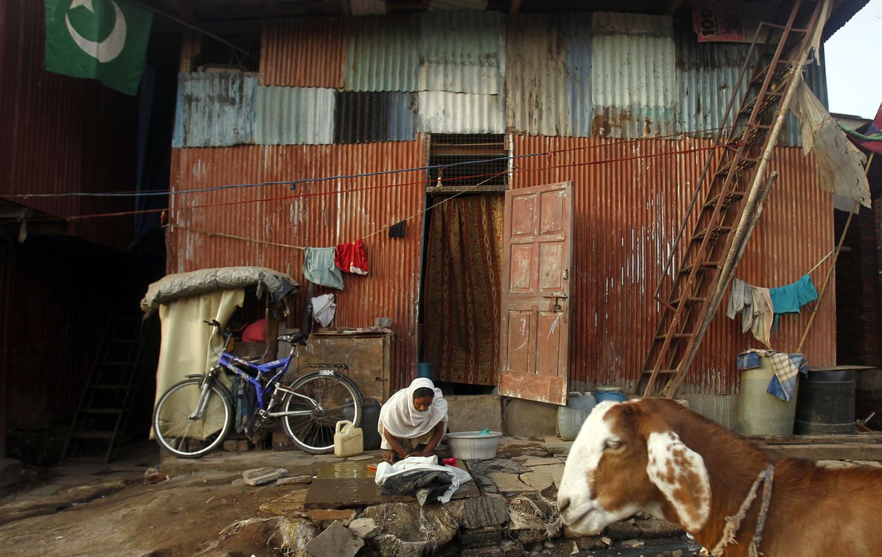 An Indian woman washes clothes outside her house in a slum on the outskirts of Mumbai, India, Thursday, March 22, 2012. UN estimates that more than one in six people worldwide do not have access to 20-50 liters (5-13 gallons) of safe freshwater a day to ensure their basic needs for drinking, cooking and cleaning. (AP Photo/Rafiq Maqbool)