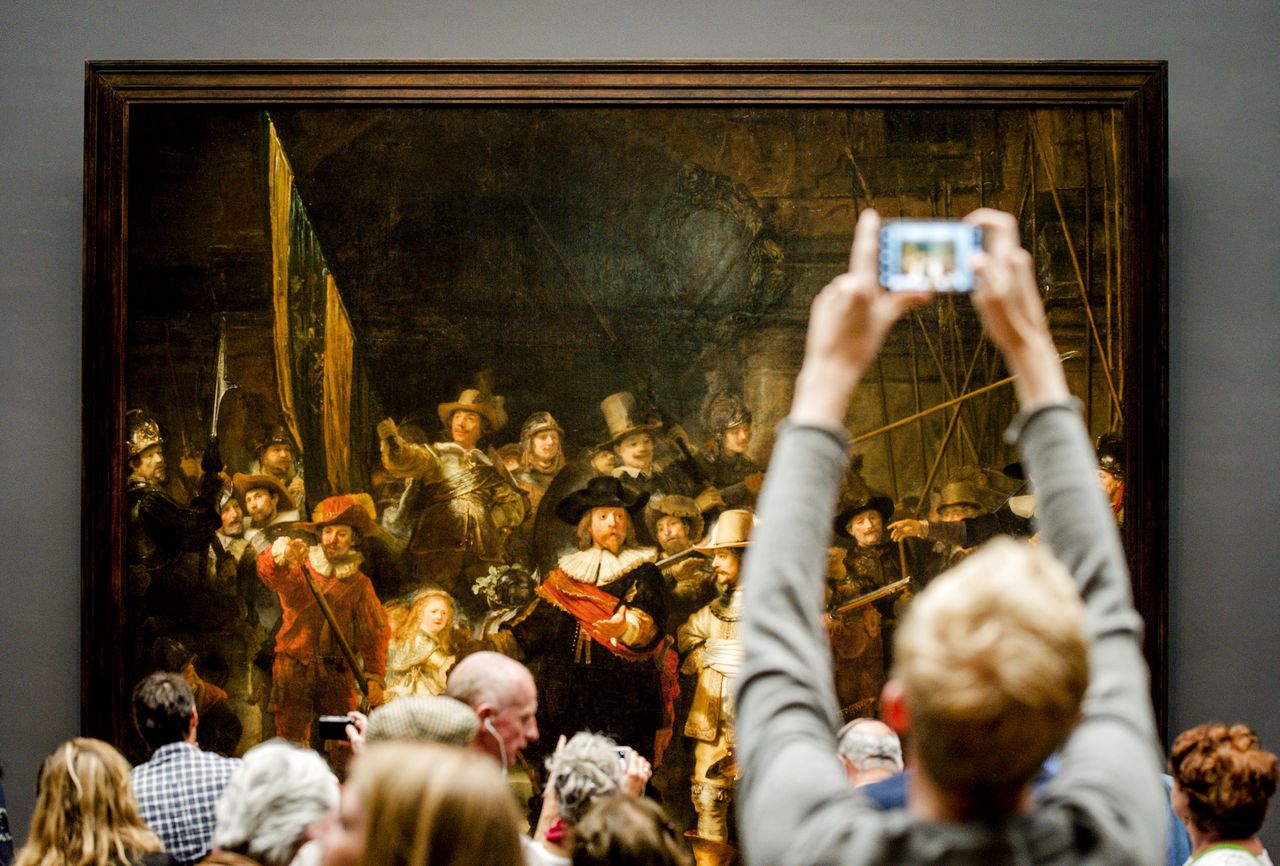 Bezoekers bekijken het schuttersstuk De Nachtwacht, het meest beroemde schilderij van Rembrandt van Rijn, in het Rijksmuseum. Foto ANP / Robin van Lonkhuijsen