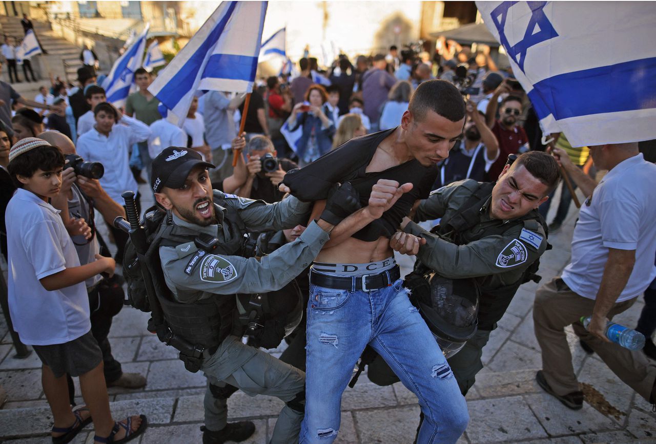 Een Palestijnse man wordt tegengehouden door Israëlische beveiligers tijdens de vlaggenmars van Israëlische nationalisten door Oost-Jeruzalem.