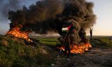 Palestijnen in de Gazastrook verbranden banden en zwaaien met de nationale vlag tijdens een protest tegen Israëlische militaire inval in de stad Jenin op de Westelijke Jordaanoever. 
