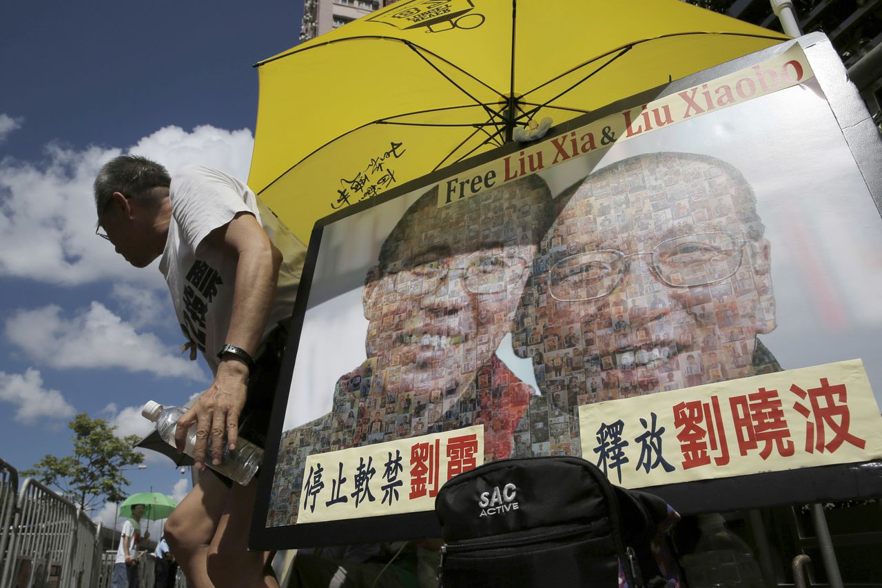Demonstranten houden in Hong Kong het portret omhoog van de Chinese dissident Liu Xiaobo en zijn vrouw Liu Xia.