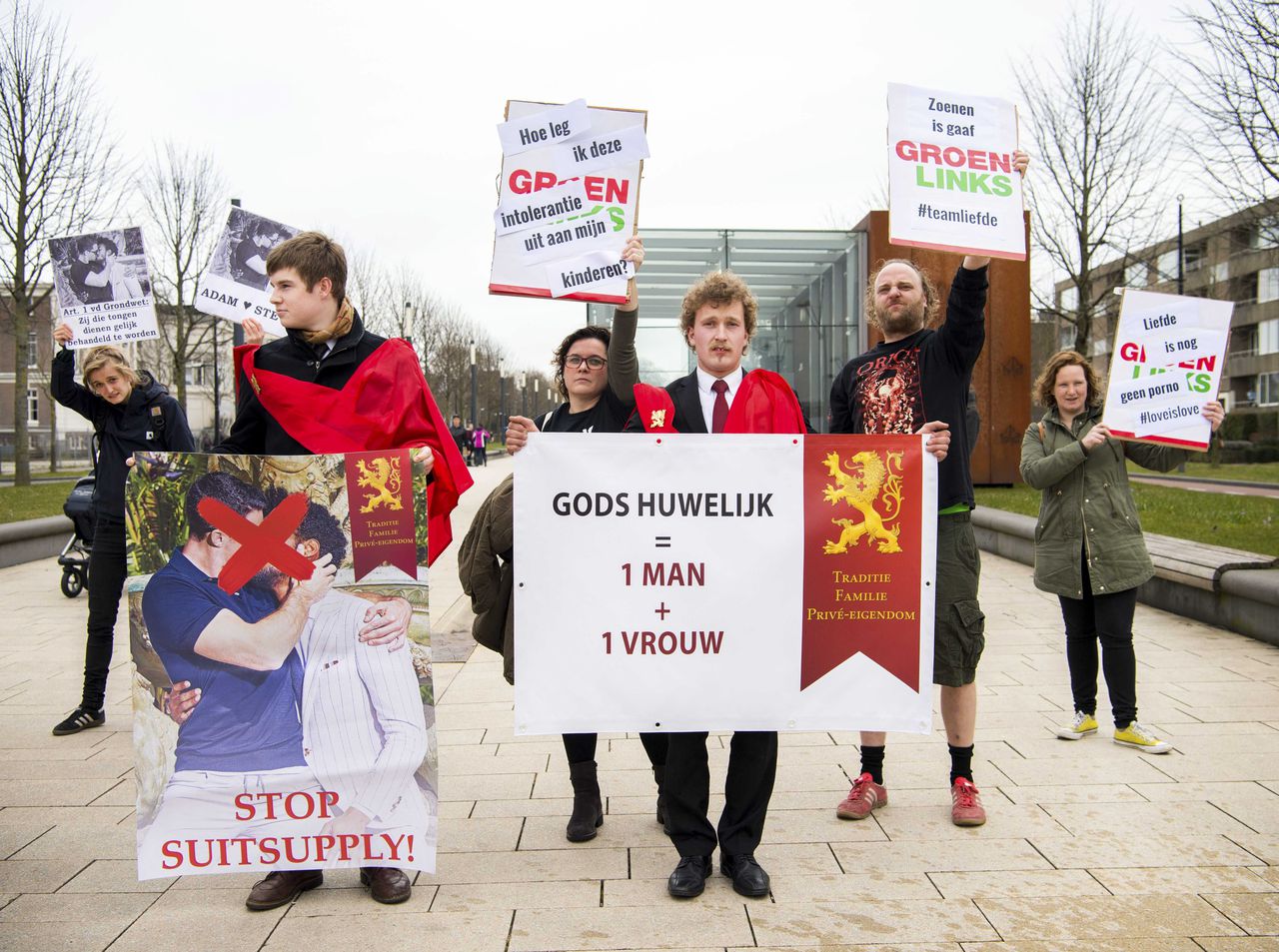 Twee leden van de stichting Civitas Christiana demonsteren in Nijmegen tegen de posters met zoenende mannen van Suitsupply. Naast hen staan tegendemonstranten van GroenLinks.