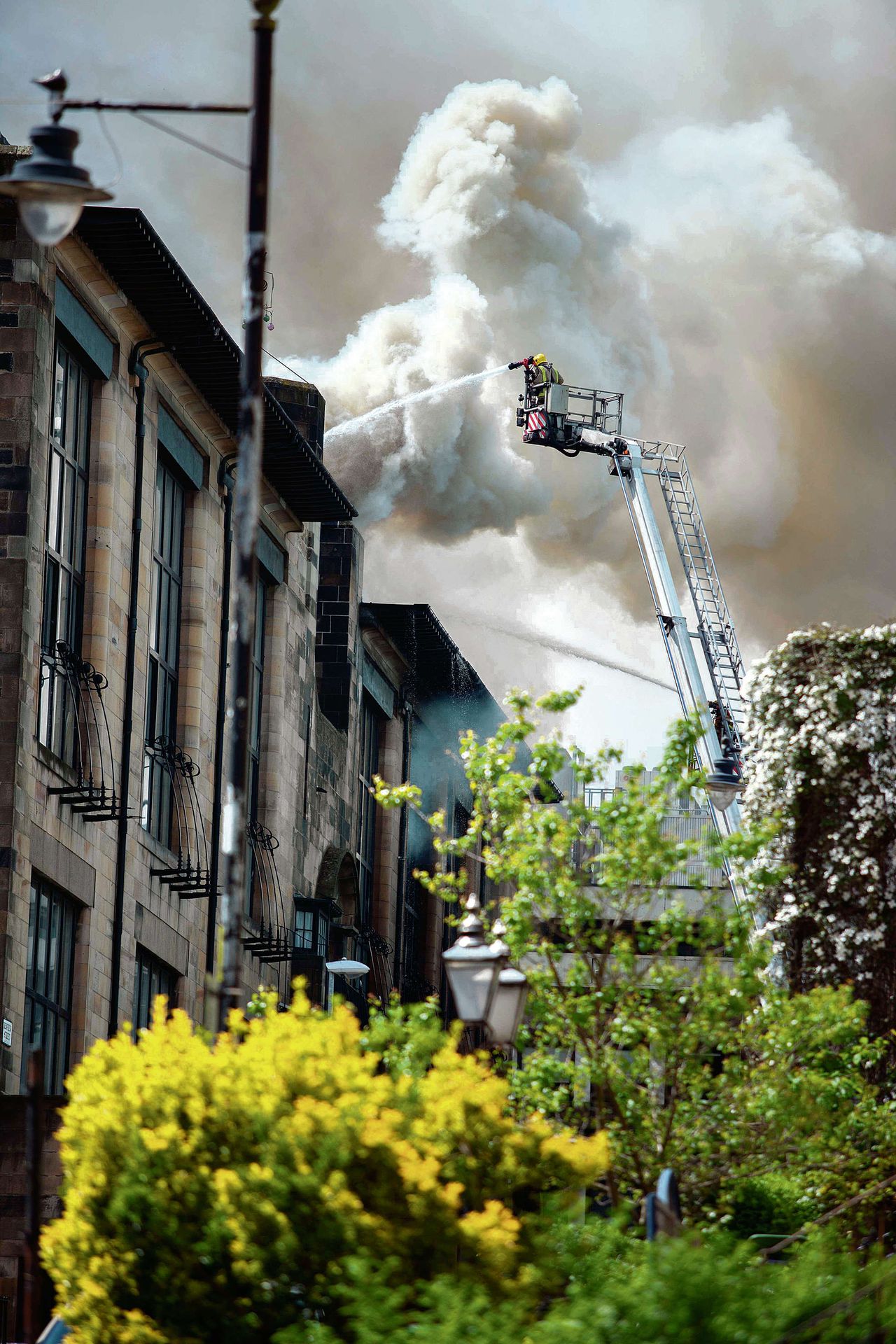 Boven: Brandweerman bezig met het blussen van de brand in Glasgow School of Art, afgelopen vrijdag.Linksonder: het interieur van de nu verwoestebibliotheek. Rechtsonder: het gebouw voor de brand.