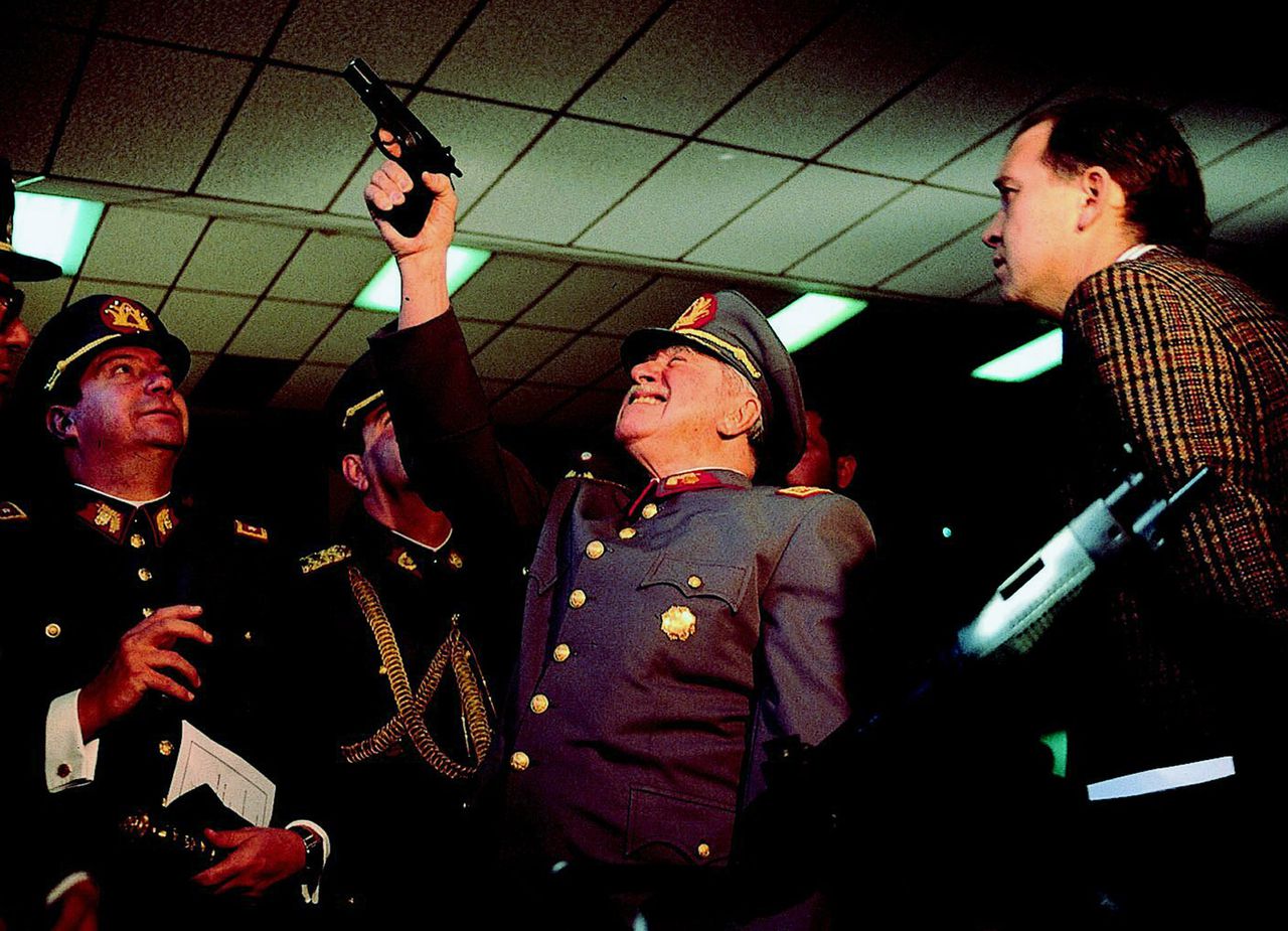 Pinochet probeert een pistool uit tijdens een bezoek aan een wapenfabriek in de Chileense hoofdstad Santiago in 1994. Onder zijn bewind werden zeker 3.000 mensen vermoord. Foto AP ** FILE ** Gen. Augusto Pinochet, center, checks a pistol during a visit to an arms factory, in Santiago, Chile, on Aug. 14, 1994. Pinochet, the fierce anti-communist dictator who ruled Chile with an iron fist from 1973 to 1990, died Sunday, Dec. 10, 2006 from heart complications, the Santiago Military hospital reported. He was 91. (AP Photo/John Perez)