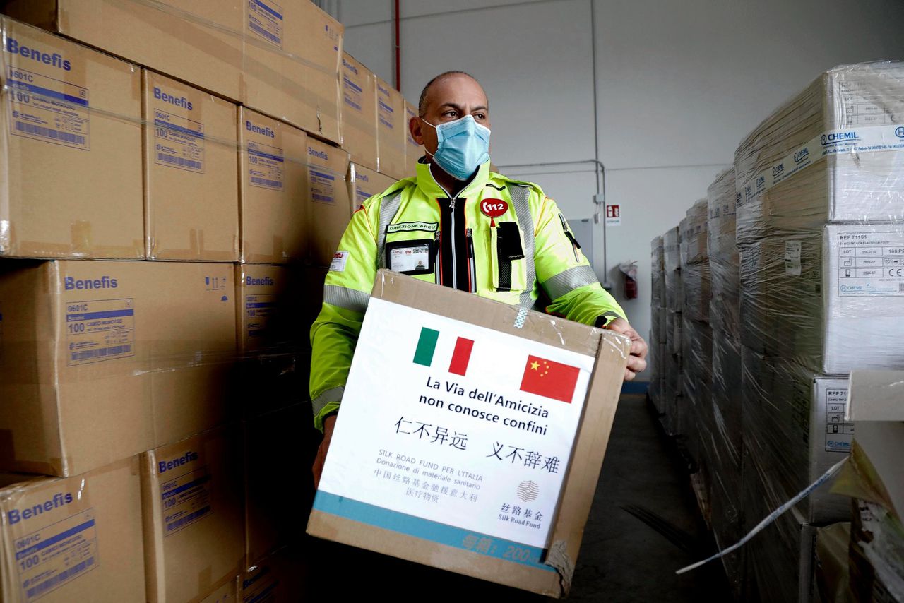 Een medewerker draagt in een magazijn bij Milaan een doos met medisch materiaal dat China heeft geschonken. Op de doos staat: „De Weg van de Vriendschap kent geen grenzen.”