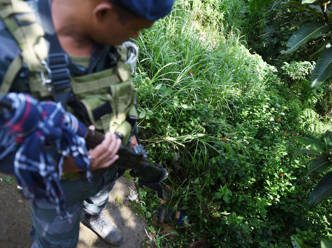 Een politieagent kijkt naar de dode lichamen van acht burgers in Marawi.