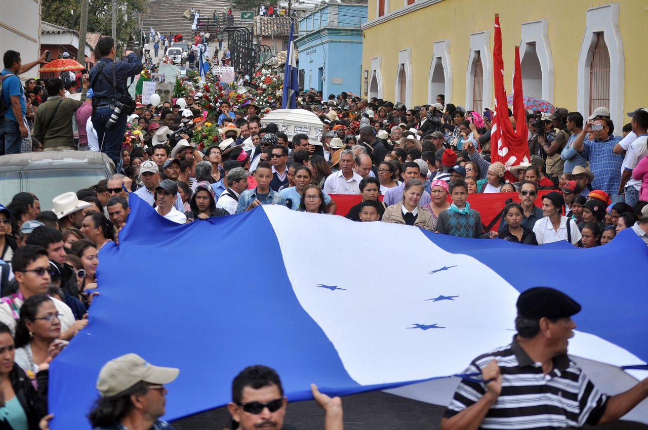 Mensen houden een Hondurese vlag in de lucht tijdens de begrafenis van milieuactivist Berta Cáceres in La Esperanza. Zij pleitte jarenlang tegen de komst van een dam en werd in 2016 doodgeschoten. FMO financierde het project.