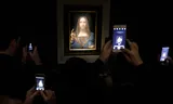 Bezoekers fotograferen het Da Vinci-schilderij tijdens een kijkdag voorafgaand aan de veiling.