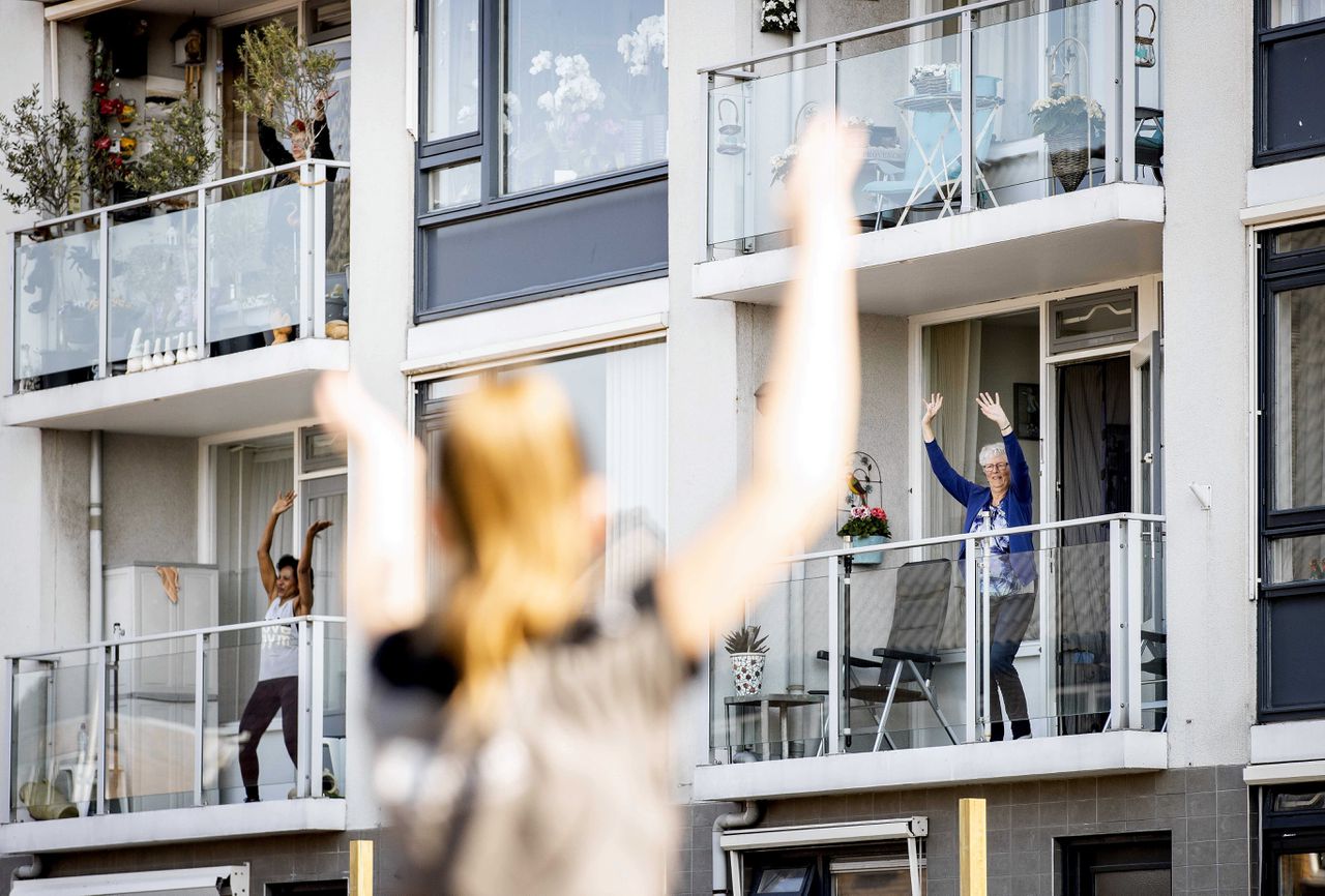 Ouderen volgen een gymles vanaf hun balkon in Kwintsheul. Door het advies om binnen te blijven tijdens de coronacrisis missen veel senioren hun dagelijkse beweging.