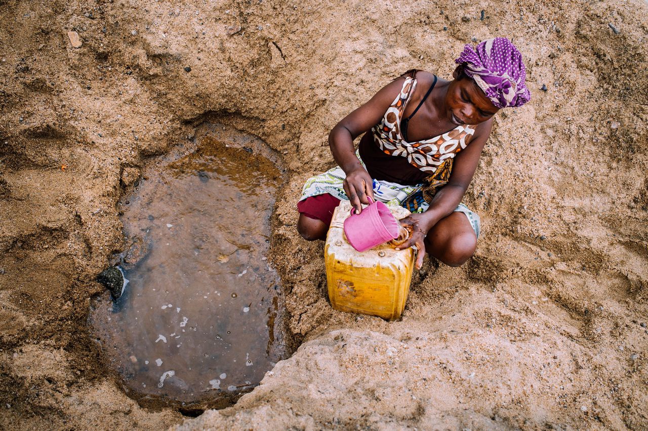 Een vrouw probeert water te verzamelen bij een poeltje in de bedding van een drooggevallen rivier. Droogte heeft geleid tot mislukte oogsten