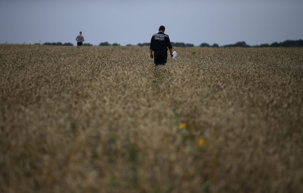 Een lid van de Oekraïense veiligheidsdienst zoekt naar slachtoffers nabij de plek waar vlucht MH17 gisteren neerstortte.