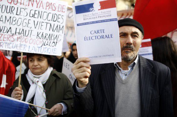 Turkish citizens from France, one of them holding a booklet reading "Electoral card", demonstrate in front of the Senate to protest against a law that would make it a crime to deny "genocide" in Armenia, in Paris, Monday, Jan. 23, 2012. Turkey threatened more sanctions for France if the Senate in Paris votes later Monday to make it a crime to deny the 20th-century killing of Armenians by Ottoman Turks constitutes a genocide. (AP Photo/Laurent Cipriani)
