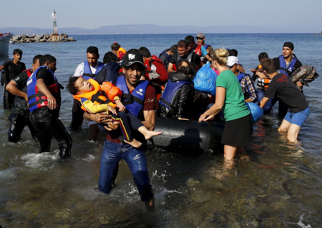 Een Syrische vluchteling draagt zijn kind op het Griekse eiland Lesbos na een barre tocht vanuit Turkije, gisteren.
