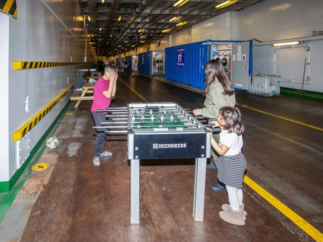 Vluchtelingenkinderen uit Syrië spelen met een voetbaltafel op het parkeerdek van de Silja.