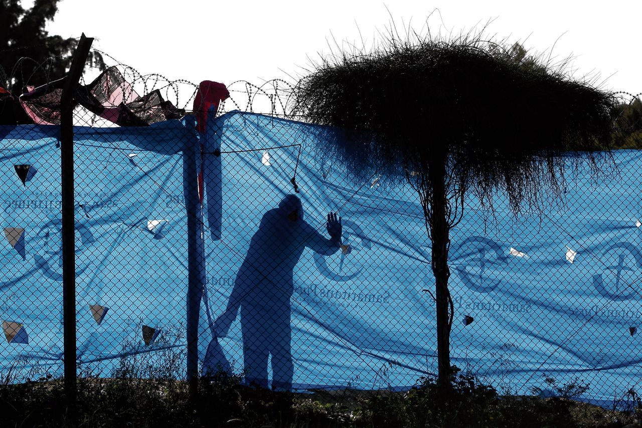 Een vluchteling achter een hek in een transitiekamp bij Athene.