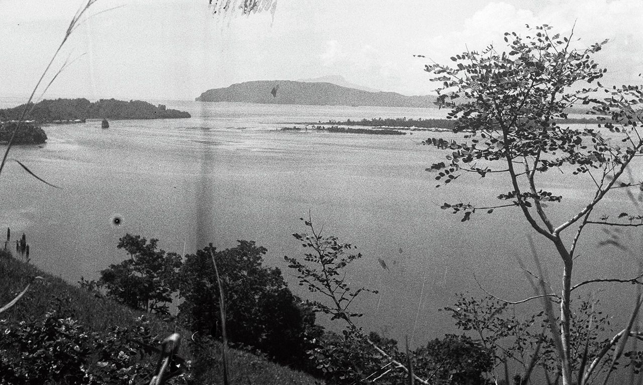 Foto van een onbekende kust met eilanden in Nederlands-Indië, gemaakt in 1947 door een onbekende fotograaf. De vlek op het beeld is een beschadiging.