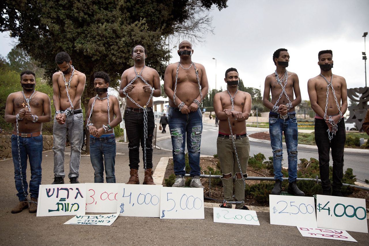 Eritrese migranten bootsen een slavenmarkt na bij de Knesset, het Israëlische parlement, om te protesteren tegen hun mogelijke uitzetting naar Rwanda of Oeganda.