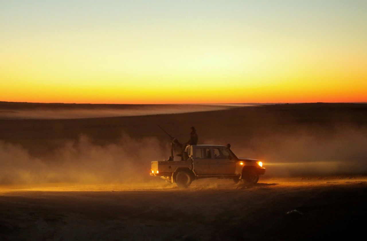 Een SDF-strijder zit zaterdag achterop een pick-uptruck vlak bij Baghouz.