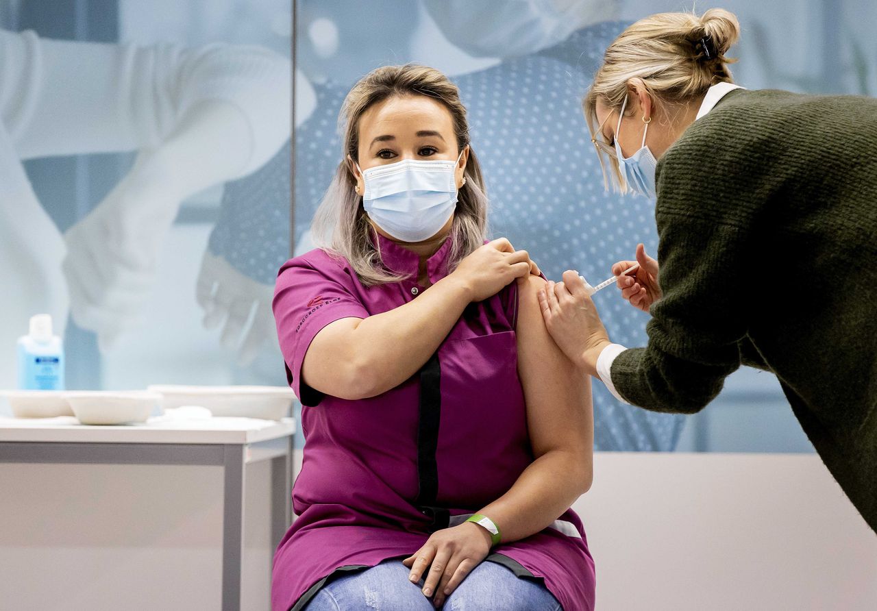 Verpleegster Sanna Elkadiri (39) van verpleeghuis Wereldhuis kreeg woensdagochtend in Veghel, onder toeziend oog van de pers en minister Hugo de Jonge (Volksgezondheid, CDA), als eerste Nederlander een coronavaccin toegediend – van de fabrikant Pfizer/BioNTech.