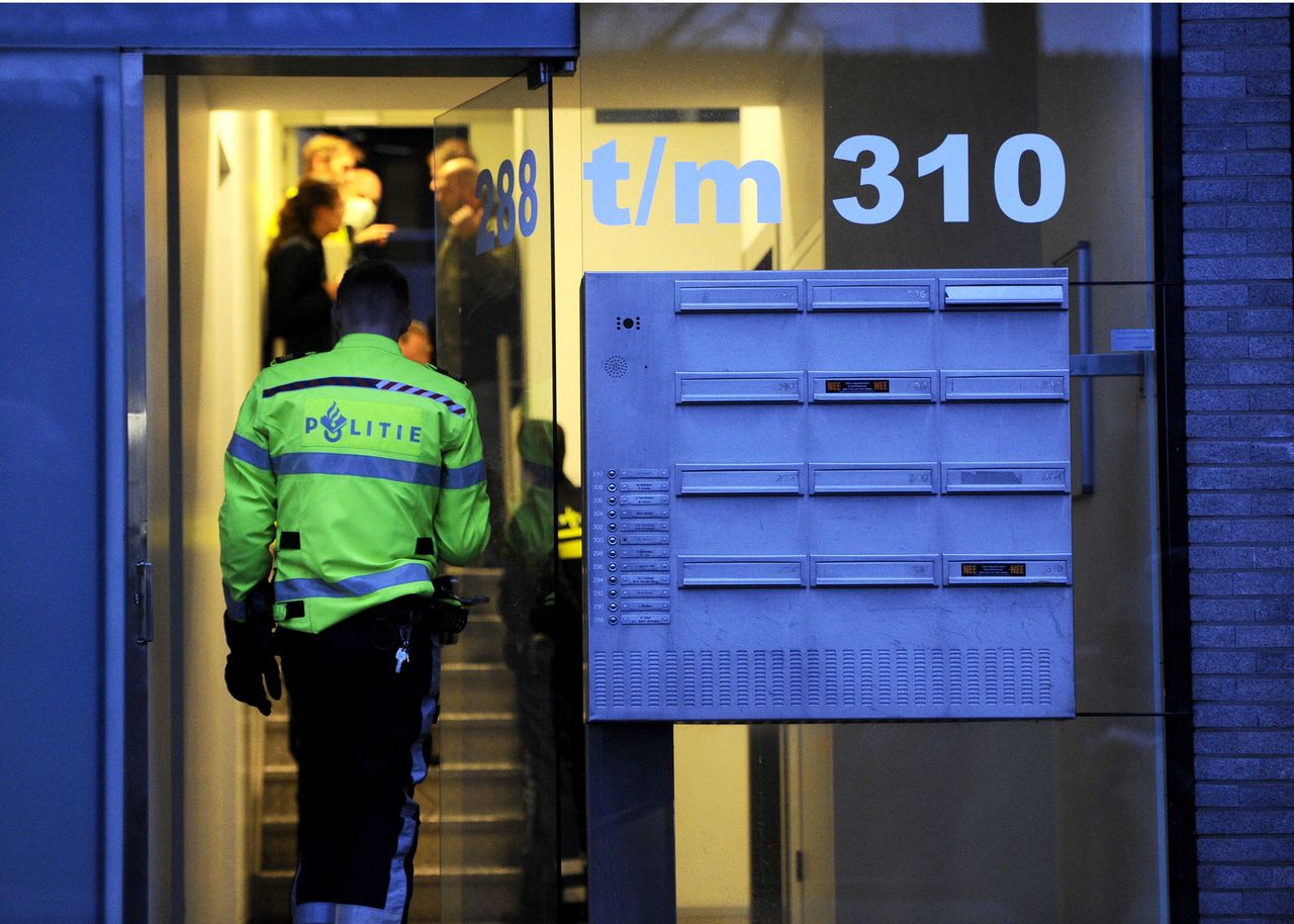 Agenten en forensisch medewerkers van de politie aan het werk in de portiek van de woning in Amsterdam.