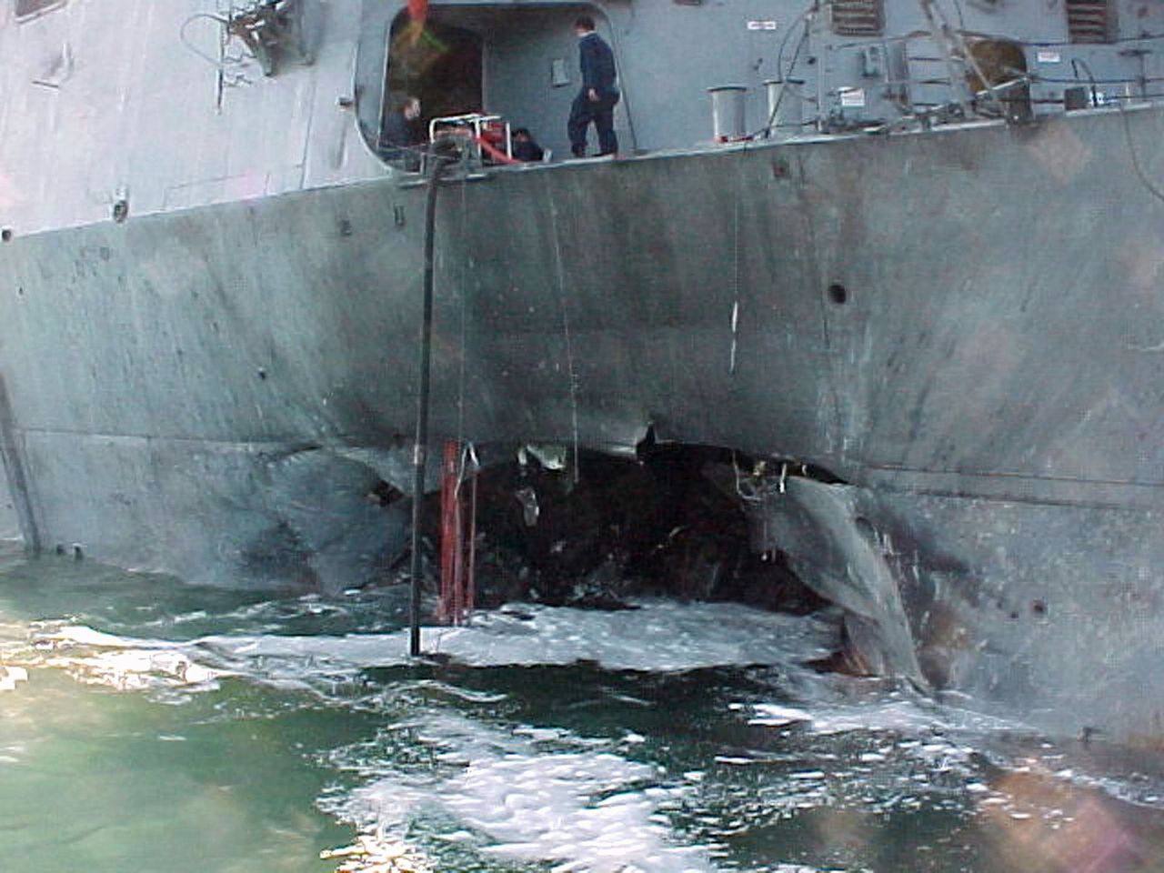De zijkant van het Amerikaanse oorlogsschip USS Cole in haven van Aden, na de zelfmoordaanslag opgeëist door al-Qaeda op 12 oktober 2000.