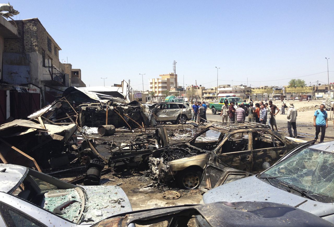 Omwonenden verzamelen op de plek van een autobomaanslag in de wijk Hurriya in Bagdad.