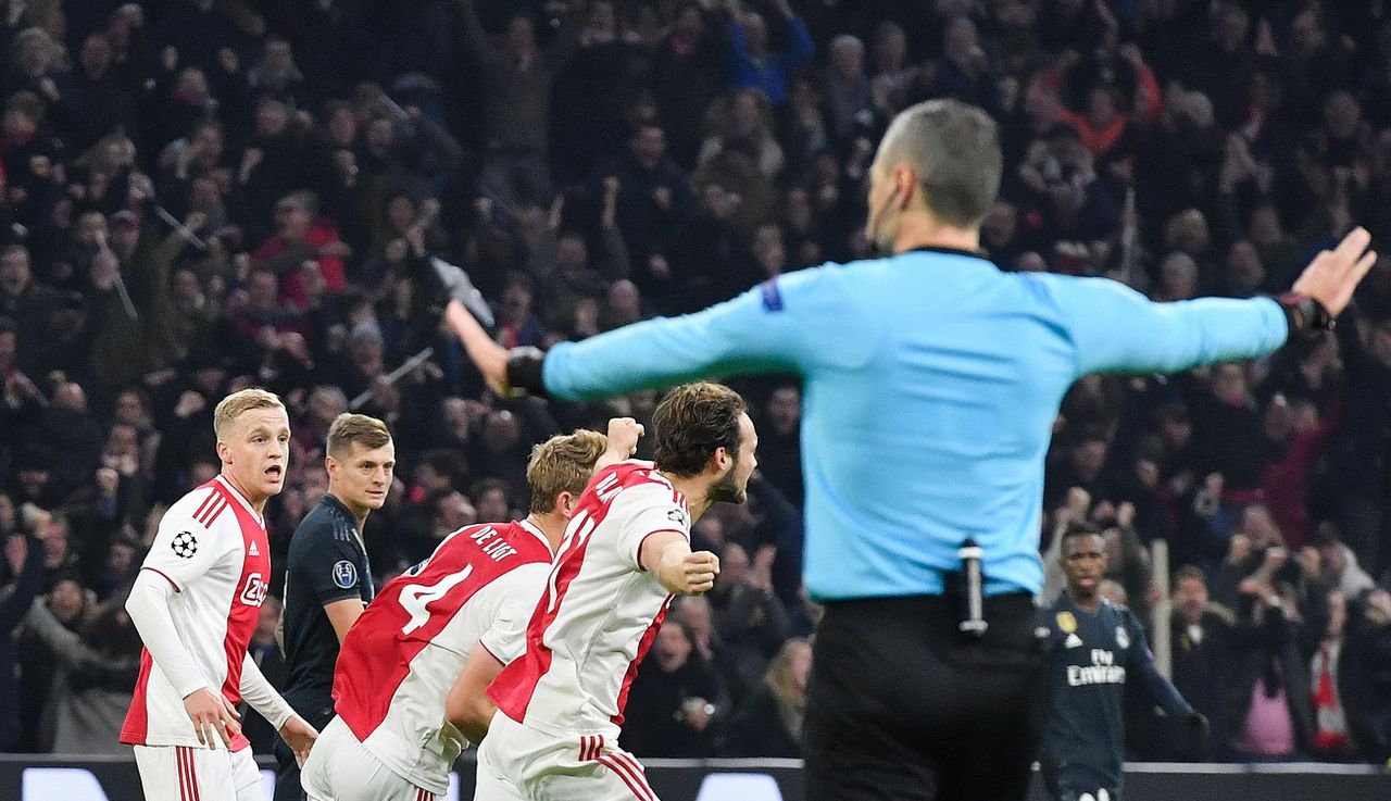 Scheidsrechter Damir Skomina gebaart, terwijl spelers van Ajax de goal van Tagliafico vieren. Het doelpunt werd na inschakeling van de VAR afgekeurd.