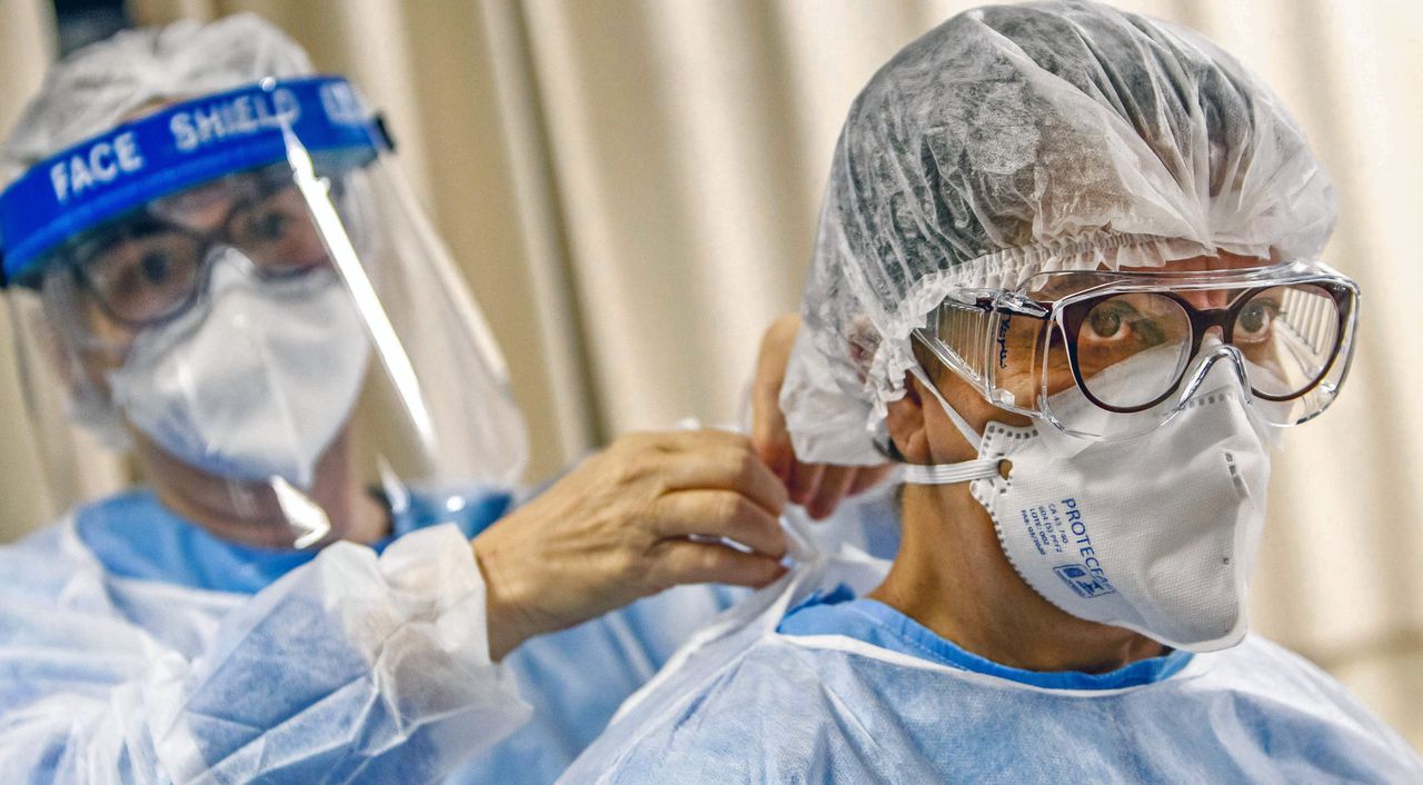 Een arts in een Braziliaans ziekenhuis brengt beschermende middelen aan bij een collega.