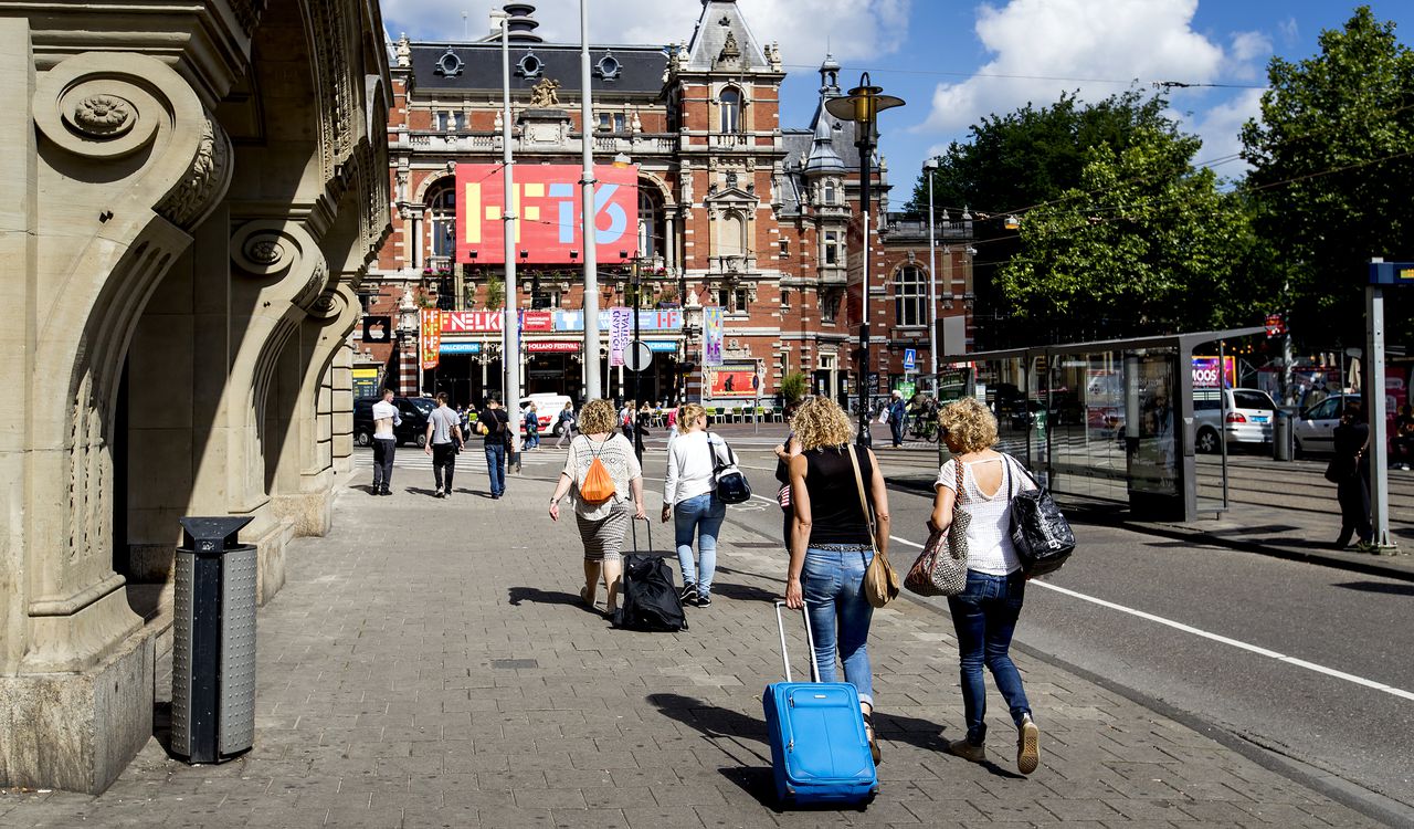 Toeristen met rolkoffers op het Leidseplein in Amsterdam.