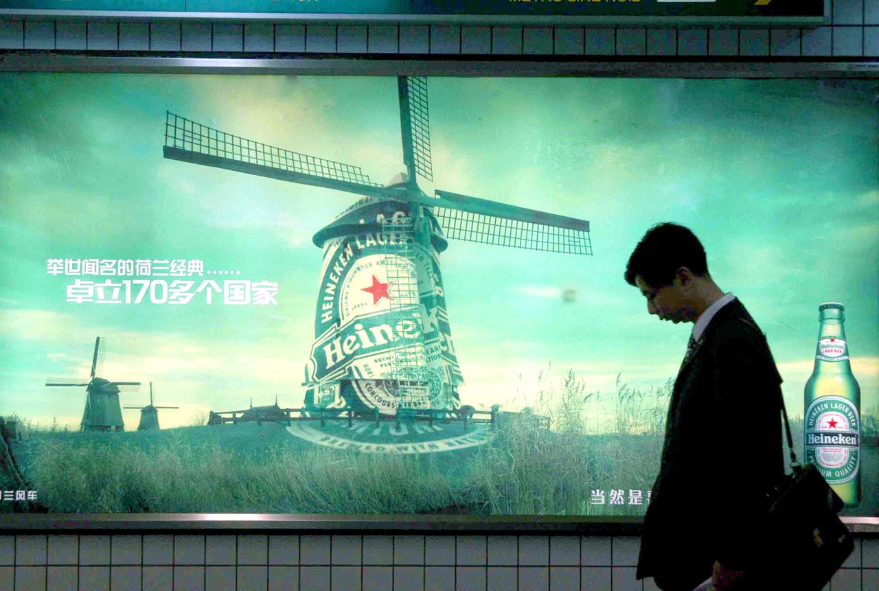 A Chinese man walks by an advertisement of Heineken beer in Shanghai 16 April 2004.