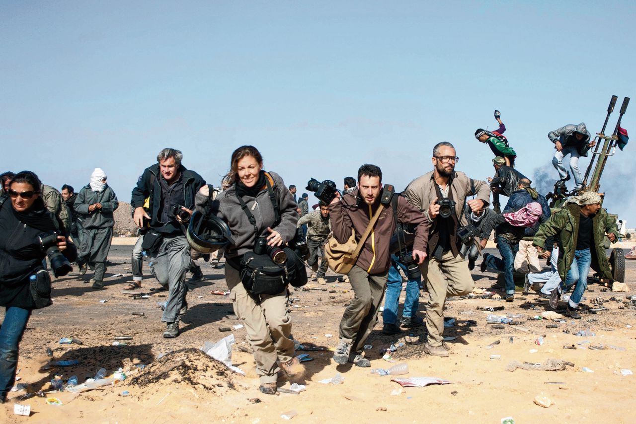 Journalisten rennen naar een gebombardeerd checkpoint bij de olieraffinaderij in Ras Lanuf, Libië. Maart 2011.