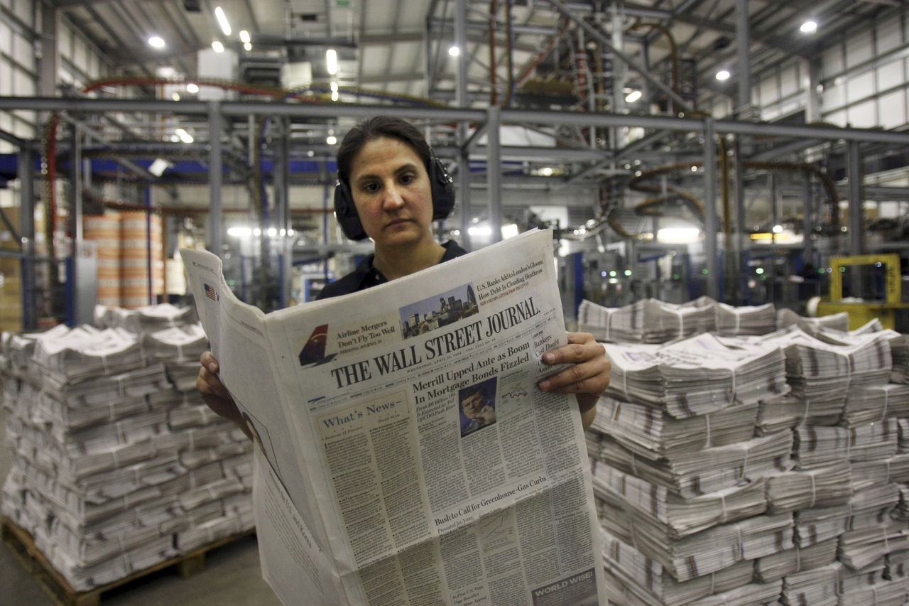 Een drukker bekijkt een nieuwe editie van The Wall Street Journal. Foto AP. Printer Belinda Affat poses for photographs with a copy of the Wall Street Journal at a printing press in London, in the early hours of Wednesday April. 16, 2008. The US edition of the Wall Street Journal was printed for the first time in London in the early hours of Wednesday morning with a batch of 3,500 copies printed for distribution around the London area. (AP Photo/Matt Dunham)