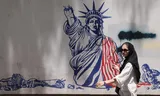 A woman walks past an anti-American wall painting near the former American embassy in Tehran.
