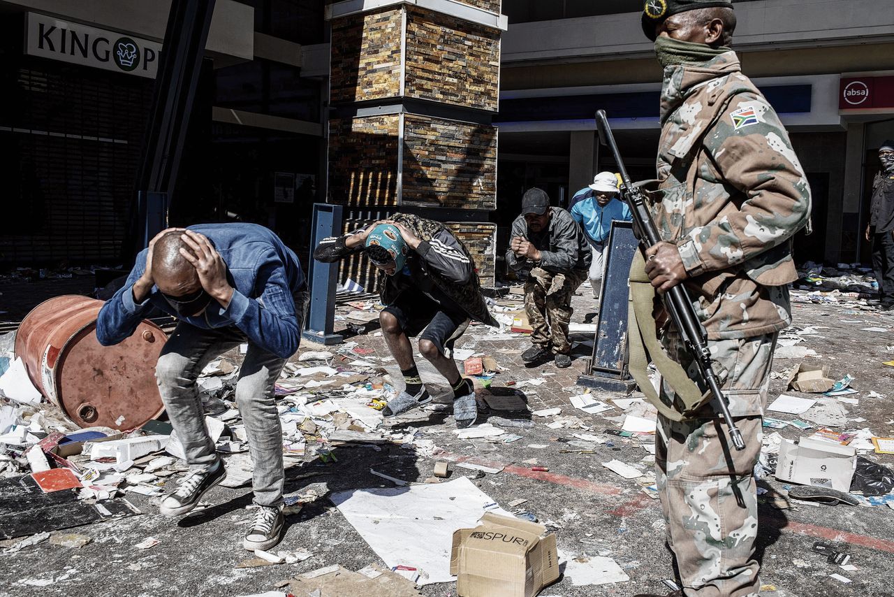 Een soldaat van het Zuid-Afrikaanse leger bewaakt bewoners van Soweto die zouden hebben meegedaan aan de plunderingen in het Jabulani-winkelcentrum in deze voorstad van Johannesburg.