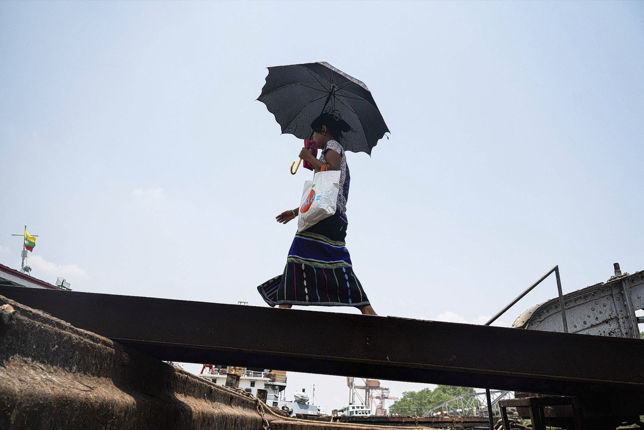 A woman walks under an umbrella to shelter from the sun as she walks on a hot day in Yangon on April 25, 2024. Extreme heat is scorching parts of South and Southeast Asia, prompting health warnings from authorities as high temperatures are recorded across the region.